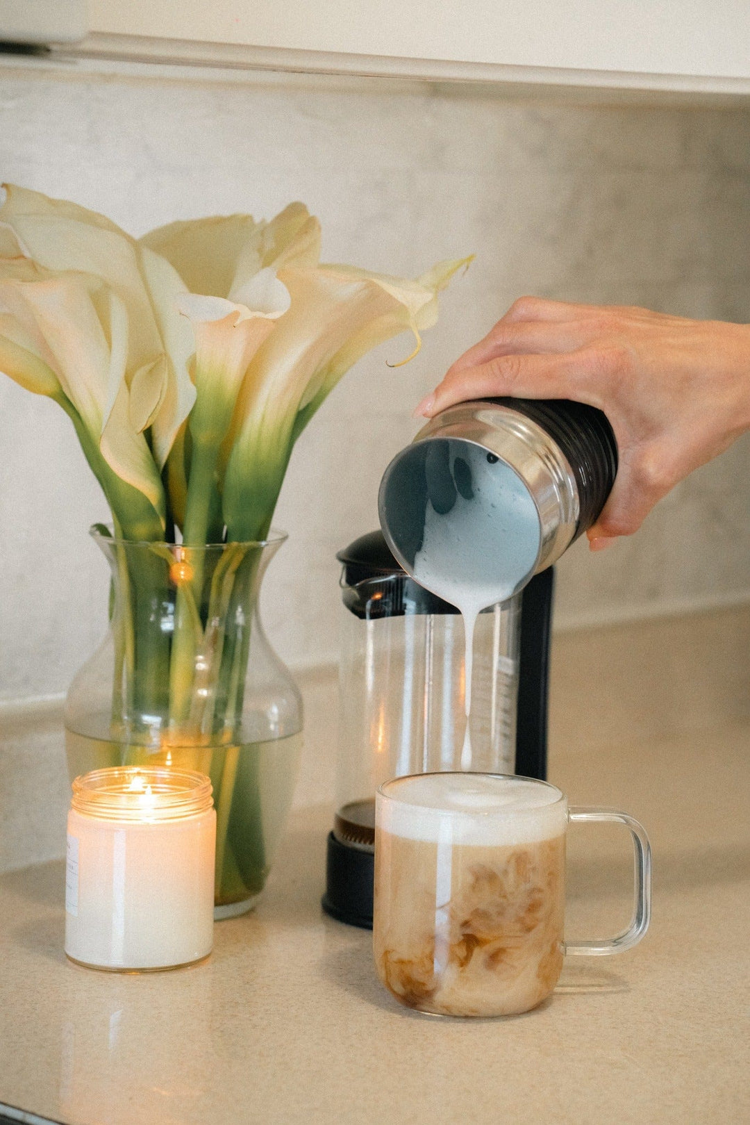 Creamy, frothy Pangea Coffee being poured into a mug in a cozy kitchen — smooth low acid coffee